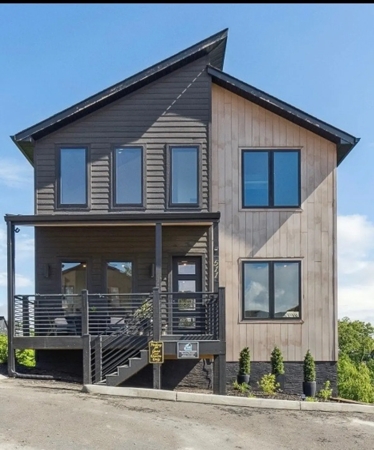 The image showcases the striking exterior of a modern, newly built cabin set against the scenic backdrop of Sevierville’s mountains. The cabin features expansive windows, a spacious front porch perfect for relaxing or socializing, and beautiful landscaping that invites guests to unwind and enjoy the natural surroundings. The mood is warm and welcoming, hinting at memorable gatherings and peaceful moments with loved ones.